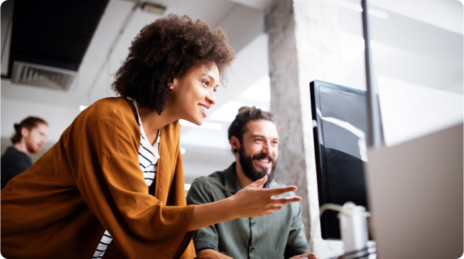 Smiling employees looking at a computer screen together