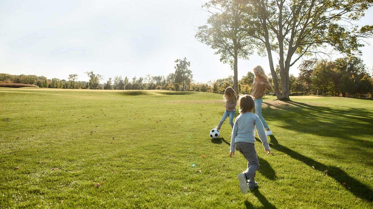 Happy family playing with a ball on meadow